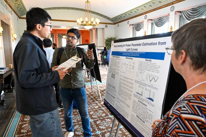 Two men and a woman discuss the project "Deep learning for pulsar parameter estimation from light curves."