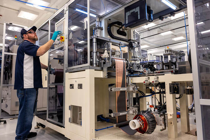 Man operating an electrode punching machine in a modern lab.