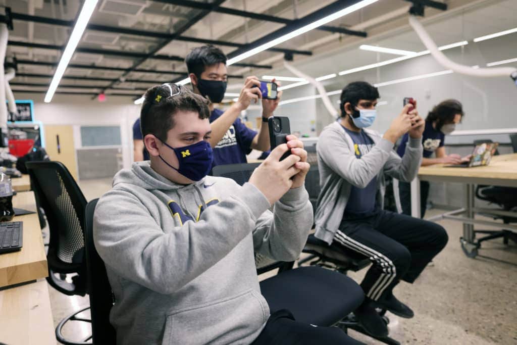 three students all shooting photos in the same direction with their phones