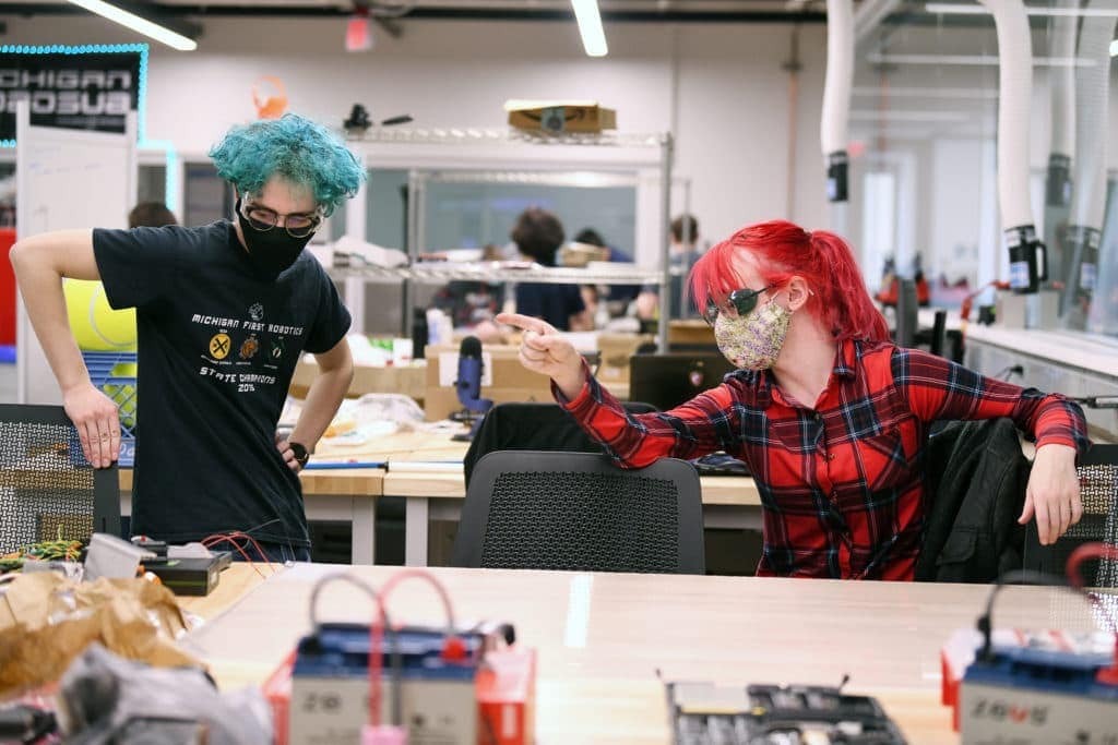 Two students at a laboratory workbench with batteries in the foreground