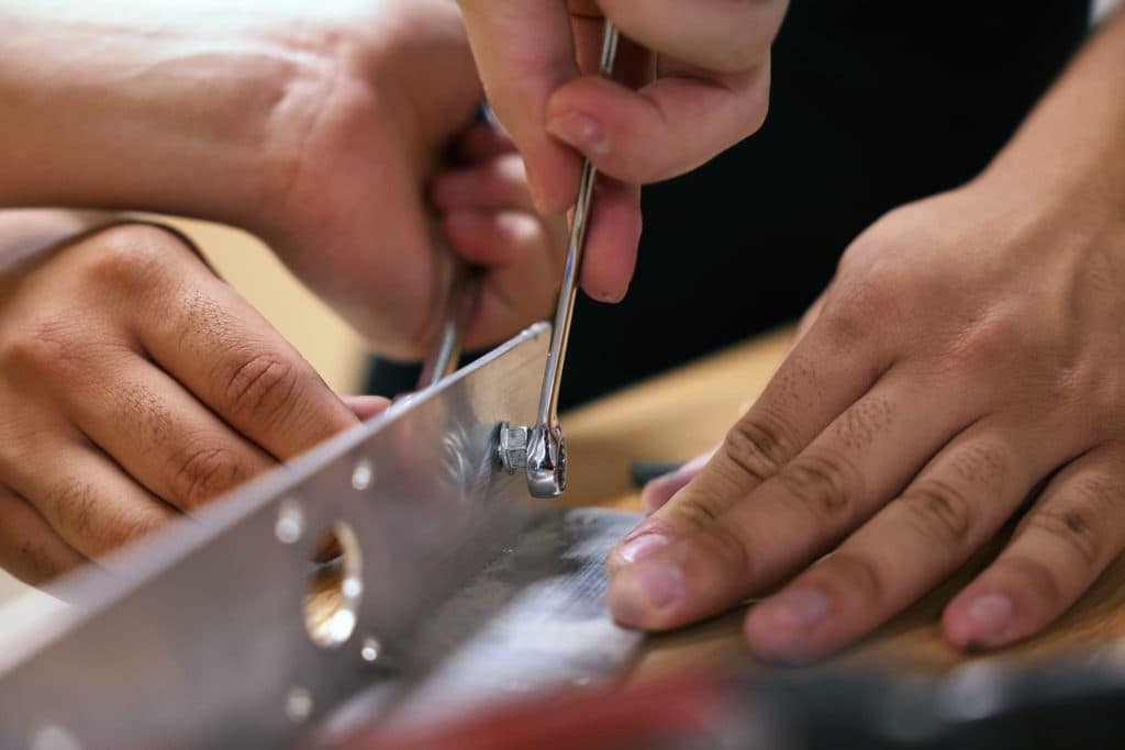 close-up of hands using a wrench to turn a bolt