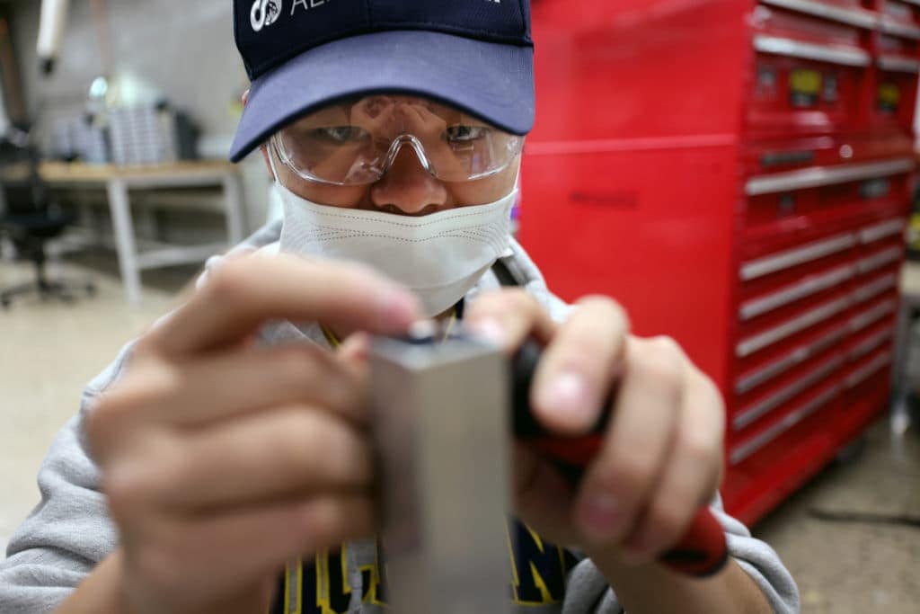 Student making adjustment to something attached to a silvery metal post