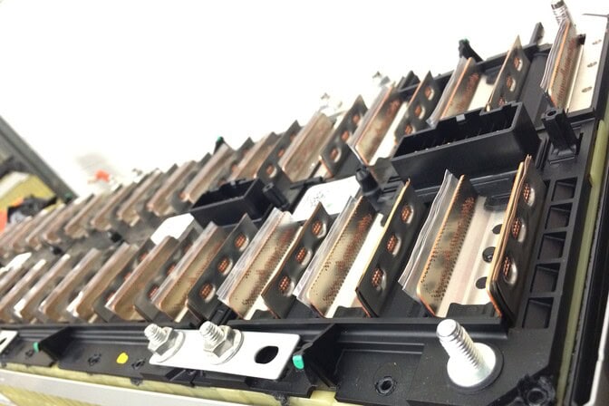 Close-up of an electric vehicle battery module with copper connectors and bolts.