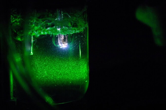 Laboratory container with glowing green liquid and bright central light source.