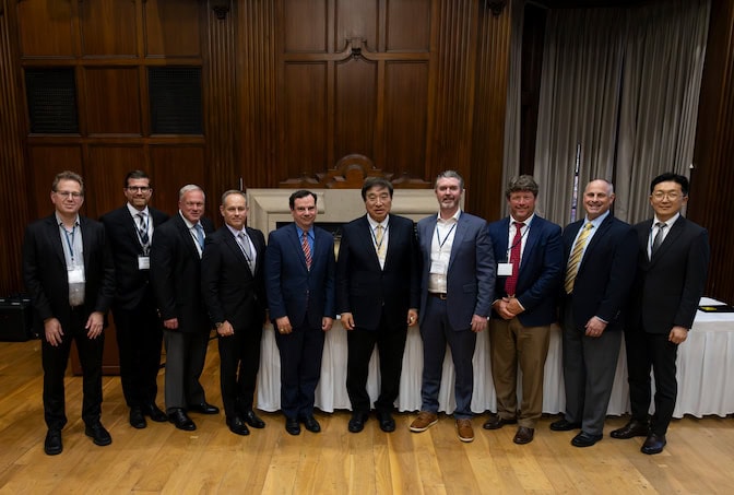 A group of men in business attire stand side by side.