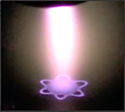 A pink beam of light radiates from the top of the frame to the bottom on a black background. Where the light comes to a point, it forms a pink star that resembles an atomic orbit.