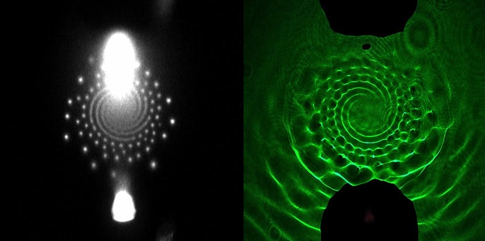 Left: A white swirl in the center of a black background. More white dots surround the swirl’s perimeter. Right: A green image forms a swirl resembling a wagon wheel or a spiraled shell. Textured waves form within the swirl’s segments. In both images, a black rounded rectangle blocks the view from the top and bottom, created by the anode and cathode.