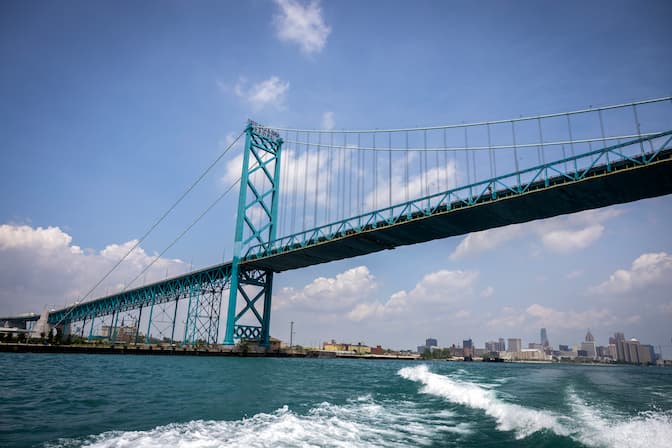A blue-green suspension bridge stretches over a river.