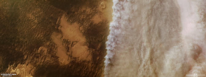 Mars's surface appears in shades of dark brown and rusty orange on the left side of the image, but dust clouds make the entire right-hand side of the image appear a pale grey.