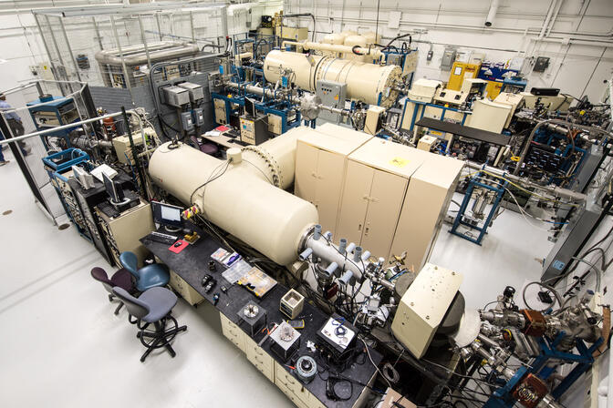 The beam lines include large beige cylinders and long silver pipes, sprouting wires in some places.