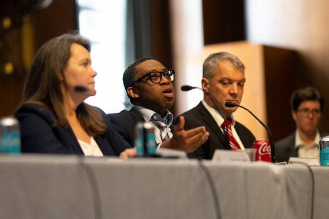 Panel discussion with four individuals at a table, each with a microphone.