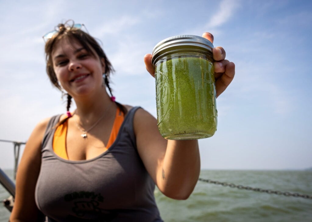 Woman holding a closed mason jar filled with green liquid