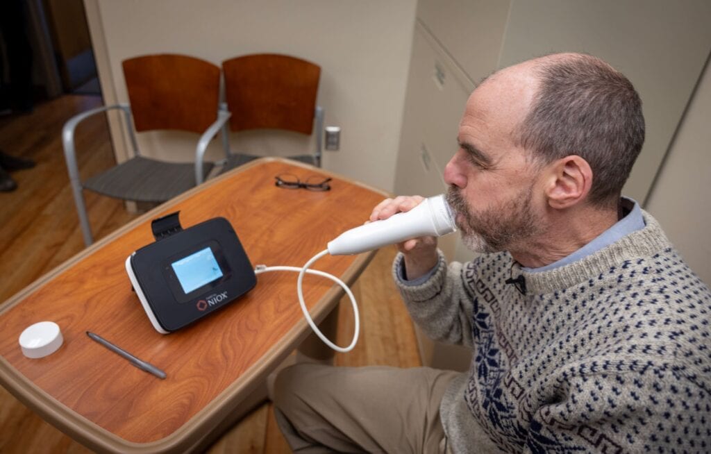 Man blowing into a handheld respiratory measurement device