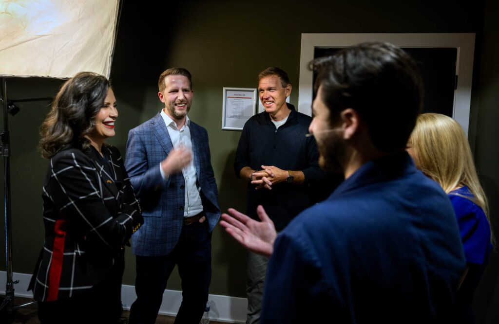 A small group of people talk and gesture during a behind-the-scenes moment at an event.