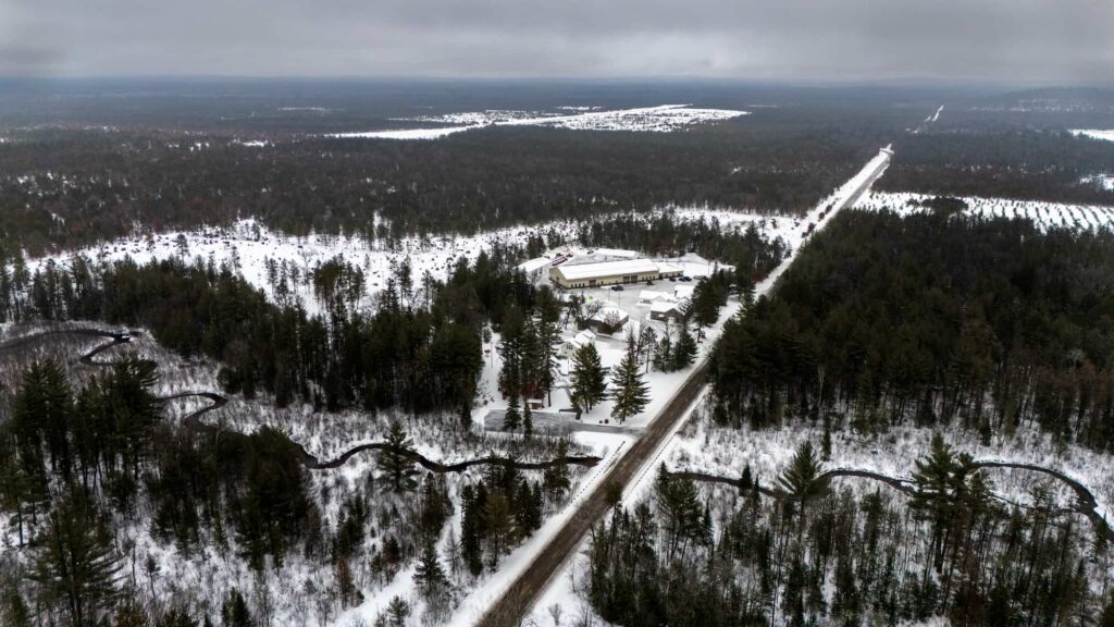 An aerial view of a winding river and a road cutting through a snow-covered forest.