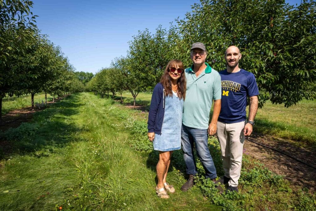  John Lyon (center), his wife Gloria Lyon and their son Chris Lyon pose at their cherry orchard.