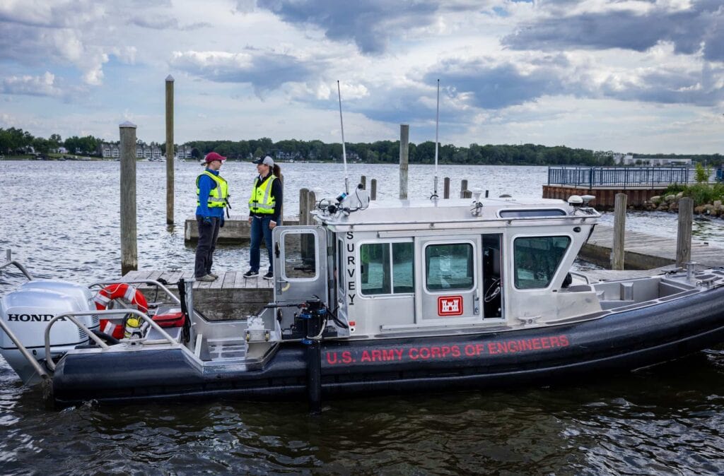 Two people talk next to a research vessel docked at the harbor.