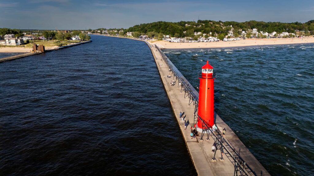 Aerial view of the Grand Haven lighthouse and pier stretching into Lake Michigan on a sunny day.
