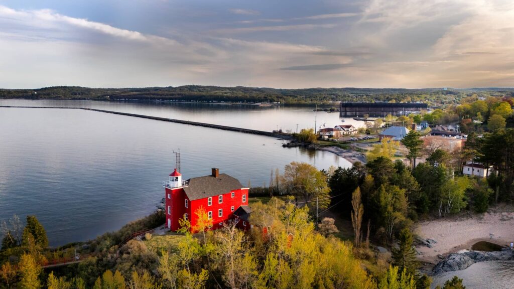 Aerial view of the red lighthouse at Marquette Harbor on the shore of Lake Superior.