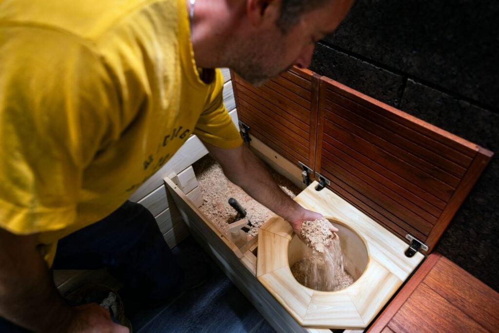 Pete Cook adds wood shavings to the composting toilet.