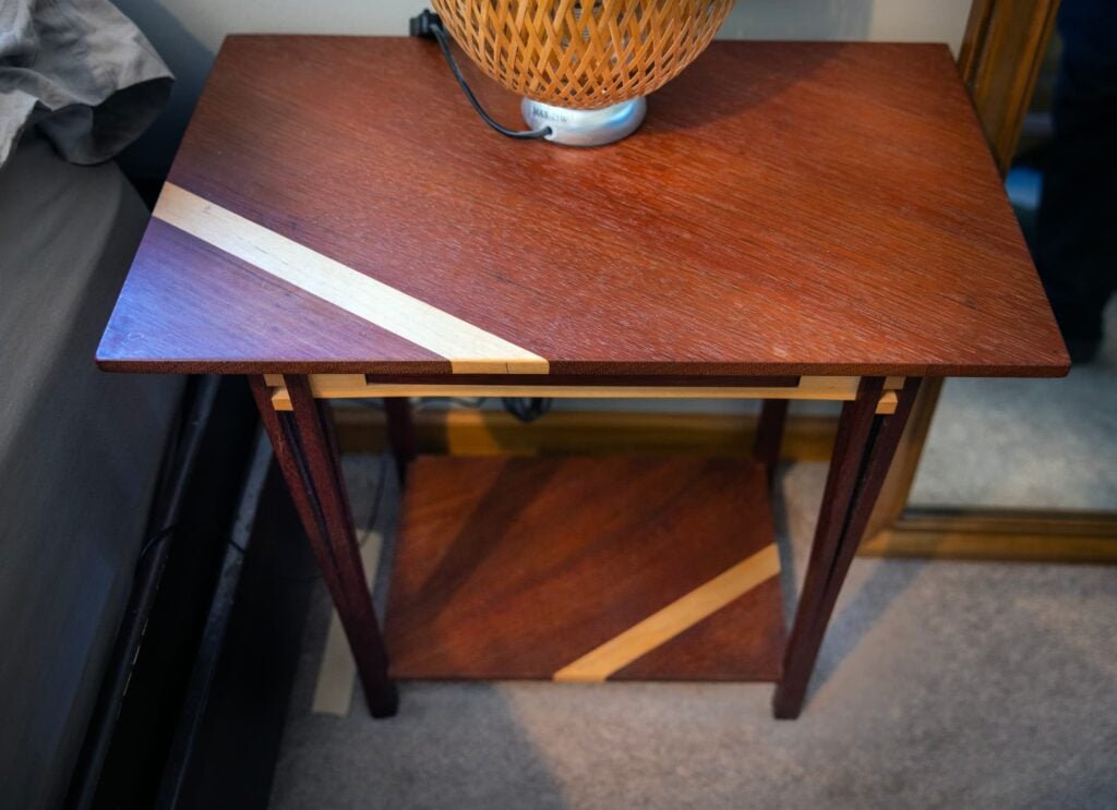 A handcrafted wooden side table showcases contrasting wood inlays and fine woodworking details.