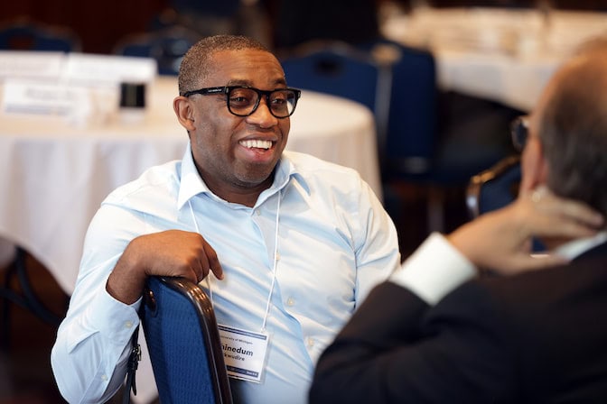 Chinedum Okwudire engaged in conversation at a table at a conference.