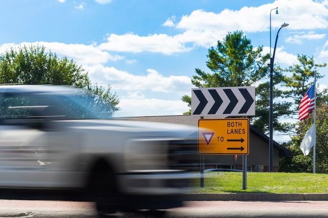 A white truck moves quickly through a roundabout intersection.